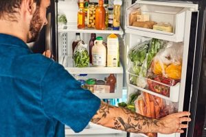 Picture of a person placing food in a fridge at Side by Side.