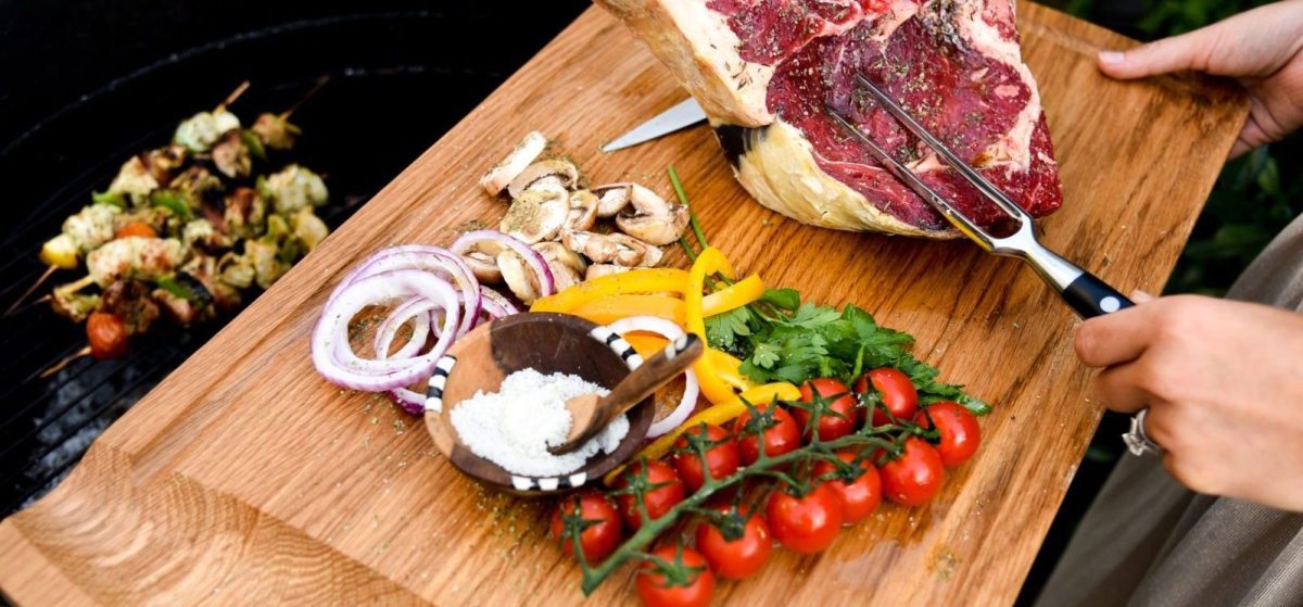 Une femme coupant de la viande sur une planche à découper-کاماپرس